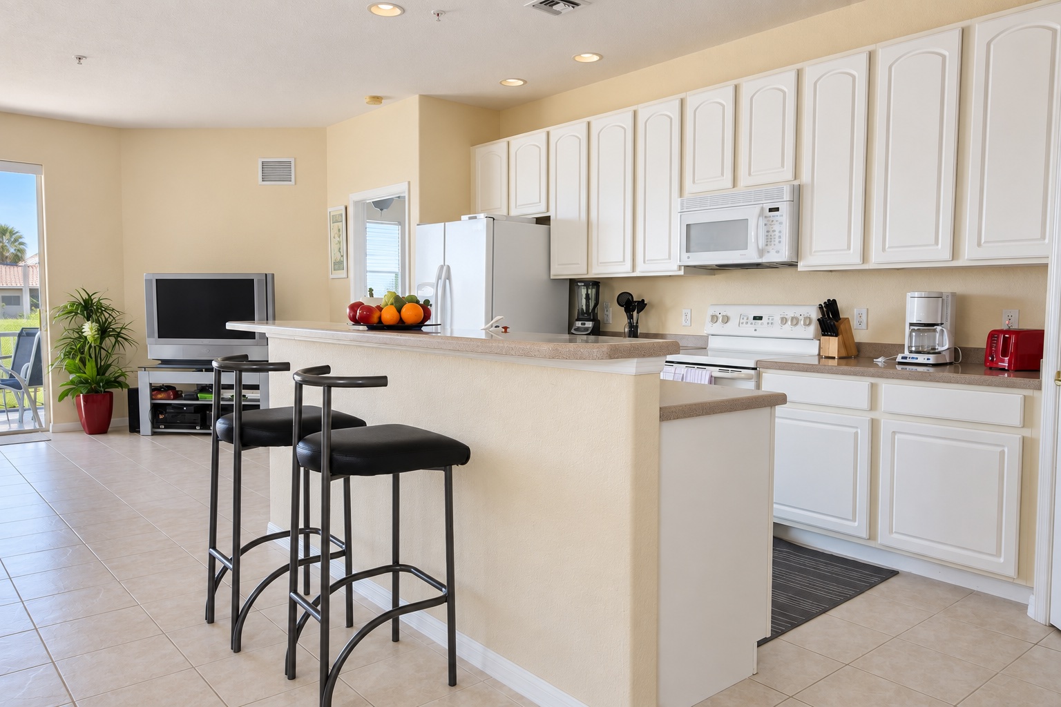 White kitchen with island, bar stools and full appliances