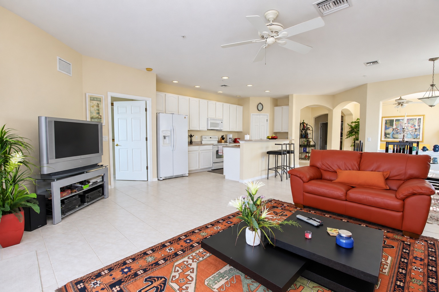 Open-plan living area with sofa, smart TV and kitchen behind
