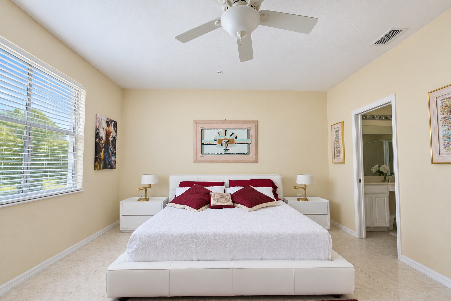 Master bedroom with white bed, red cushions and bright window