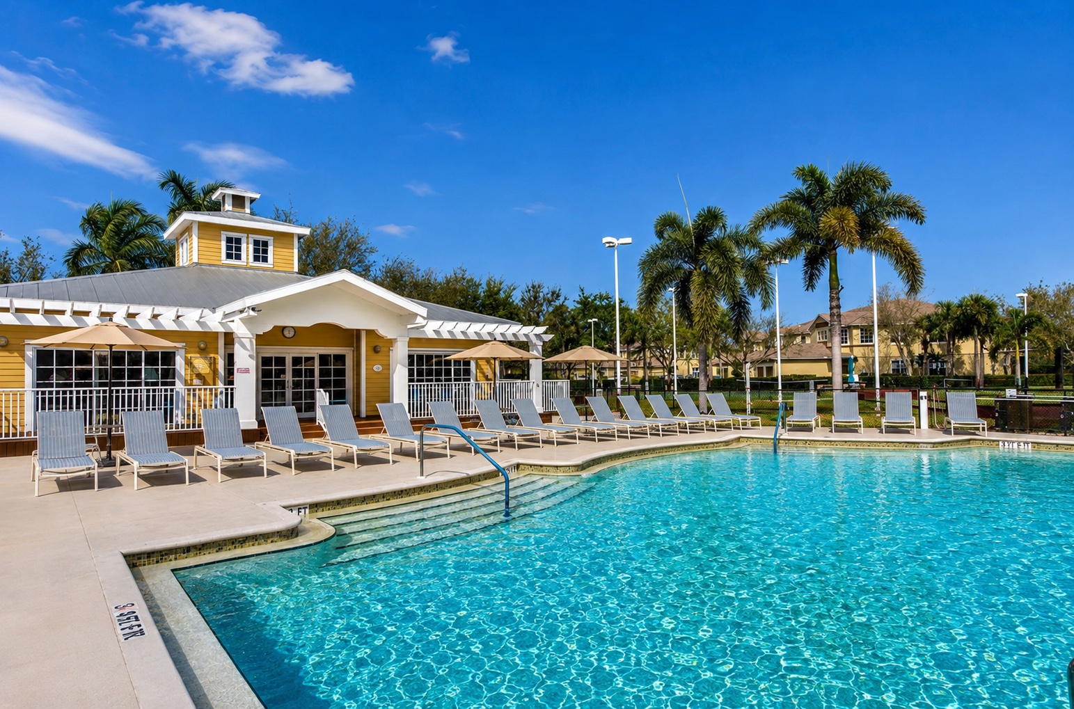 Community resort pool with clear water, sun loungers and clubhouse